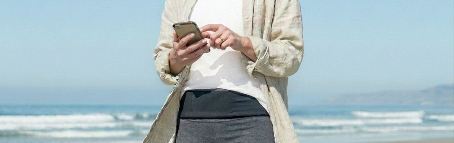 woman in pink top and blue leggings with a tie Dye pocketed Belt on at a beach