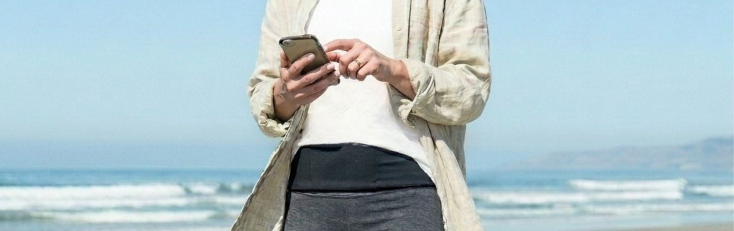woman in pink top and blue leggings with a tie Dye pocketed Belt on at a beach