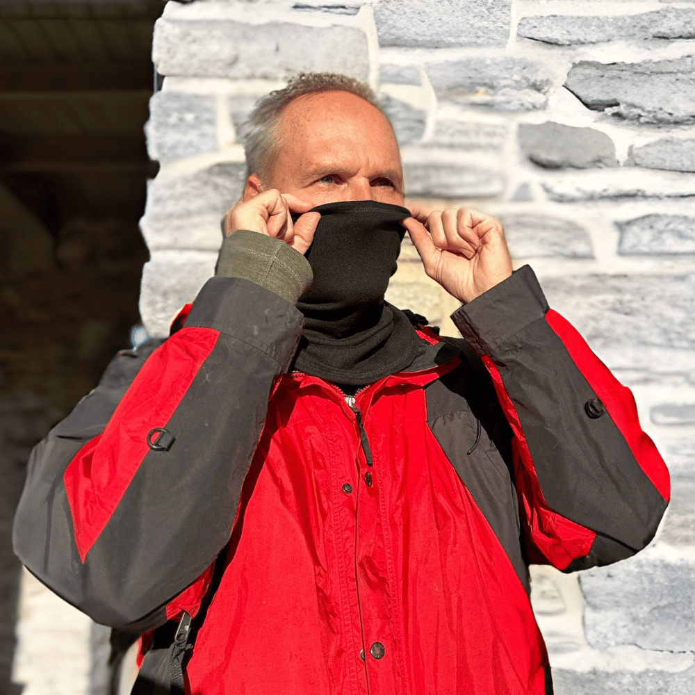 Man wearing black cozy wrap and pulling it around nose and mouth.