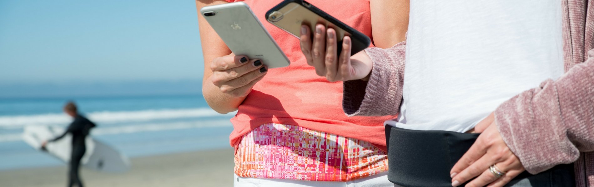 two models on their phone at the beach wearing bandi pocketed wrap