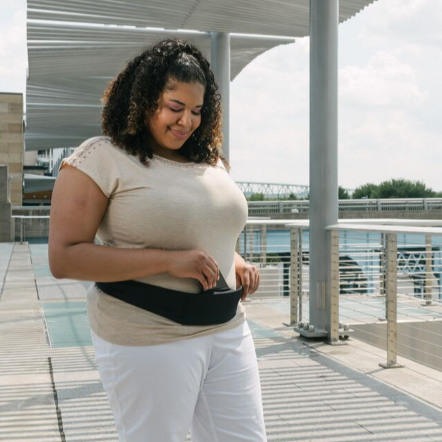 full figure woman wearing Black BANDI Pocketed belt. She is smiling as she is looking down at her phone coming out of the pocket.