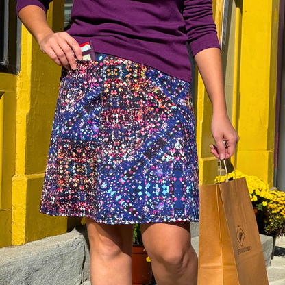 Person wearing a colorful navy patterned skirt with a purple top demonstrating the big pockets on this BANDI skirt