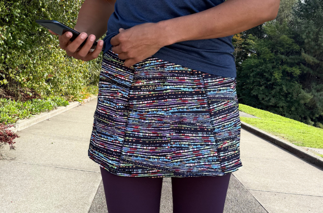 Person wearing a colorful patterned skirt and blue top outdoors on a path.